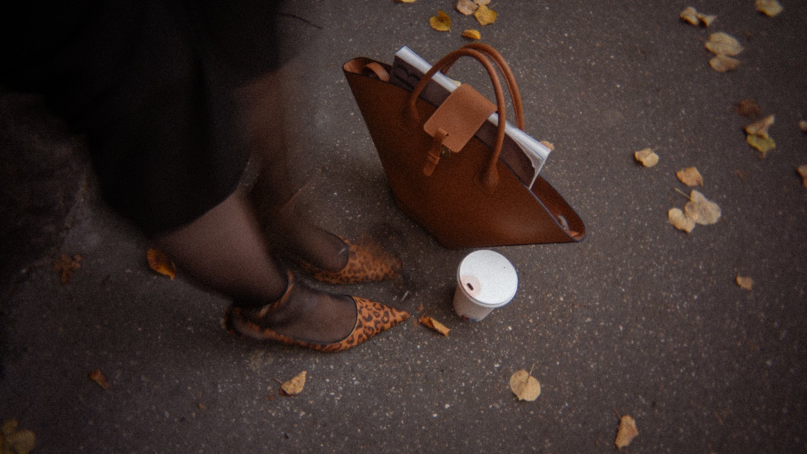 A leather tote and leopard mules on wet asphalt, an editorial frame from our own shoot