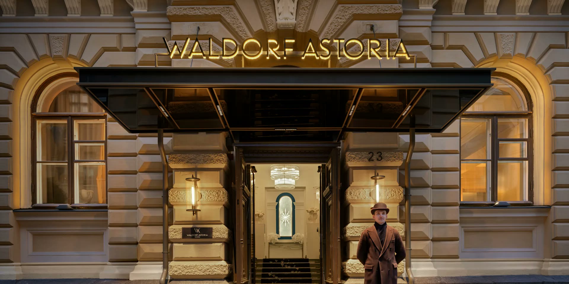 Waldorf Astoria Helsingin sisäänkäynti hämärässä, ovimies valaistun katoksen alla